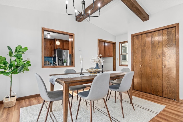 dining area featuring a notable chandelier, baseboards, light wood-type flooring, and vaulted ceiling with beams