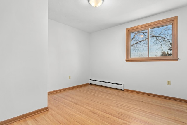 empty room with a baseboard radiator, baseboards, and light wood finished floors