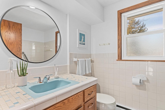 bathroom featuring wainscoting, vanity, toilet, and tile walls