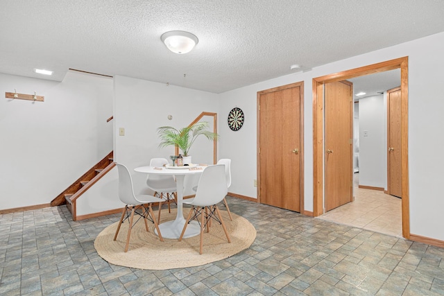 dining area with stone finish flooring, baseboards, a textured ceiling, and stairs