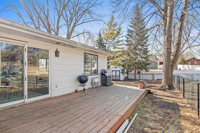 wooden deck with an outbuilding, a shed, a fenced backyard, and area for grilling