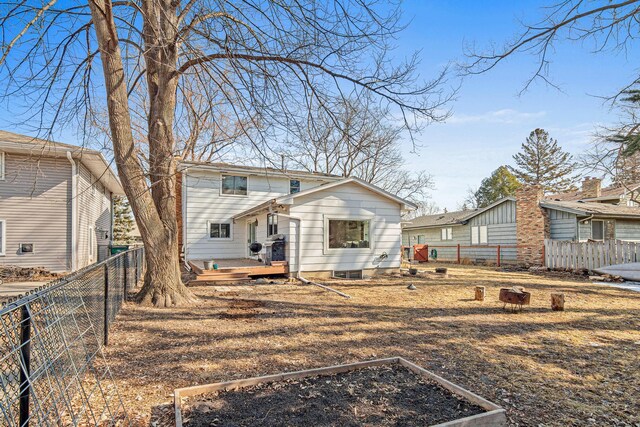 back of house with a deck, a fenced backyard, and a garden