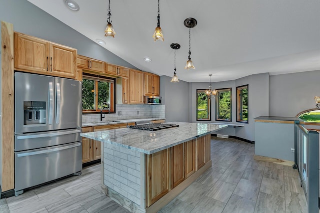 kitchen featuring tasteful backsplash, lofted ceiling, appliances with stainless steel finishes, light stone countertops, and a sink