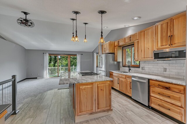 kitchen featuring a center island, stainless steel appliances, backsplash, vaulted ceiling, and a sink