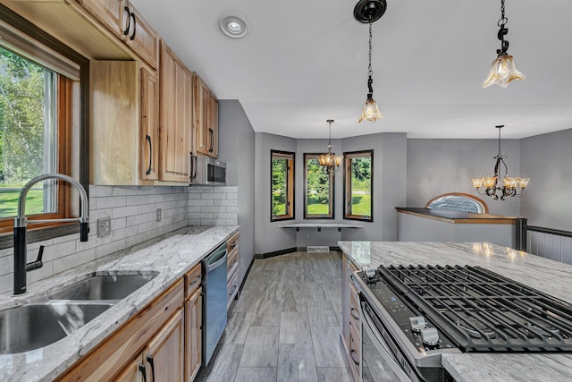 kitchen with a sink, appliances with stainless steel finishes, backsplash, decorative light fixtures, and an inviting chandelier