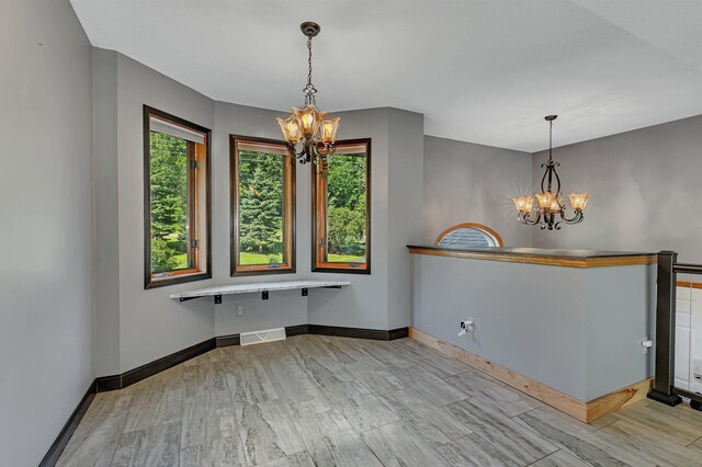 interior space featuring visible vents, a notable chandelier, baseboards, and wood finished floors