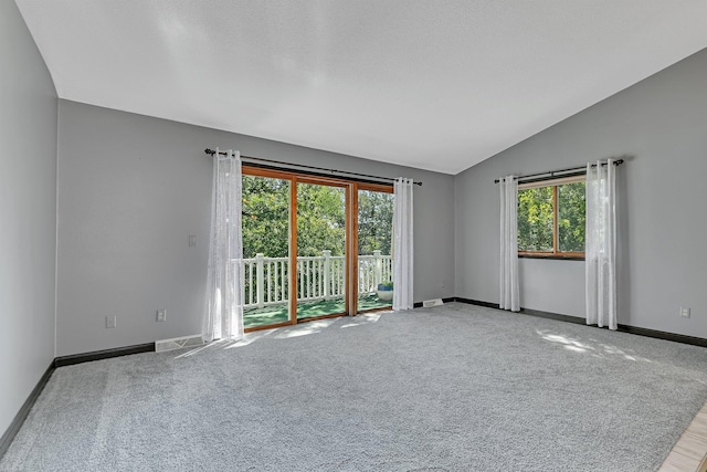 carpeted spare room featuring lofted ceiling, visible vents, and baseboards