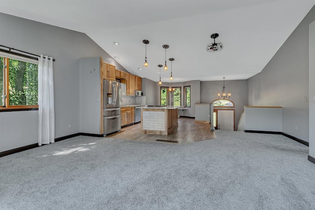 kitchen featuring light carpet, appliances with stainless steel finishes, vaulted ceiling, and an inviting chandelier