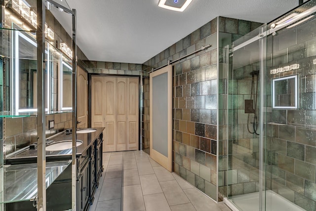 bathroom featuring double vanity, a sink, a shower stall, a textured ceiling, and tile patterned floors