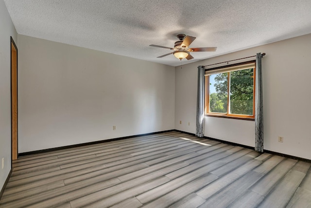 spare room featuring light wood-type flooring, ceiling fan, a textured ceiling, and baseboards