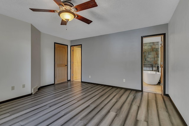 unfurnished room featuring a textured ceiling, baseboards, and wood finished floors