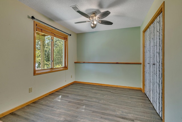 unfurnished room with a ceiling fan, a textured ceiling, baseboards, and wood finished floors