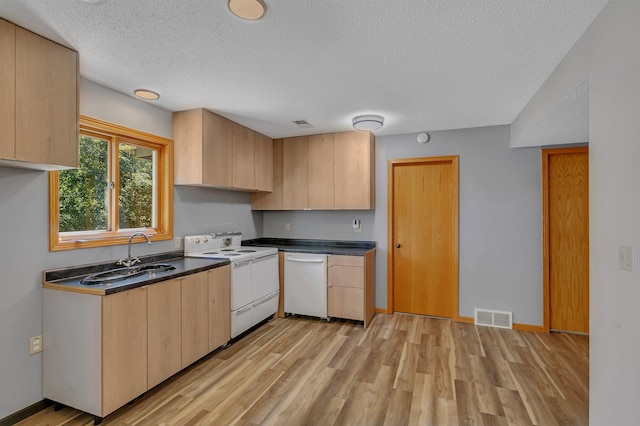 kitchen featuring dark countertops, visible vents, light brown cabinetry, a sink, and white appliances