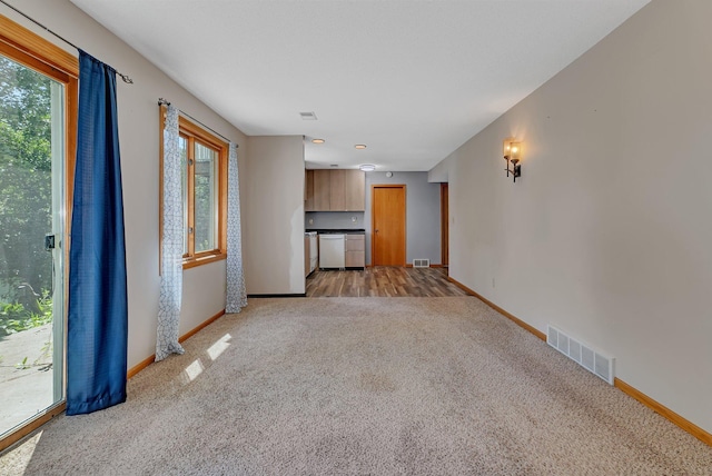 unfurnished living room featuring light colored carpet, visible vents, and baseboards