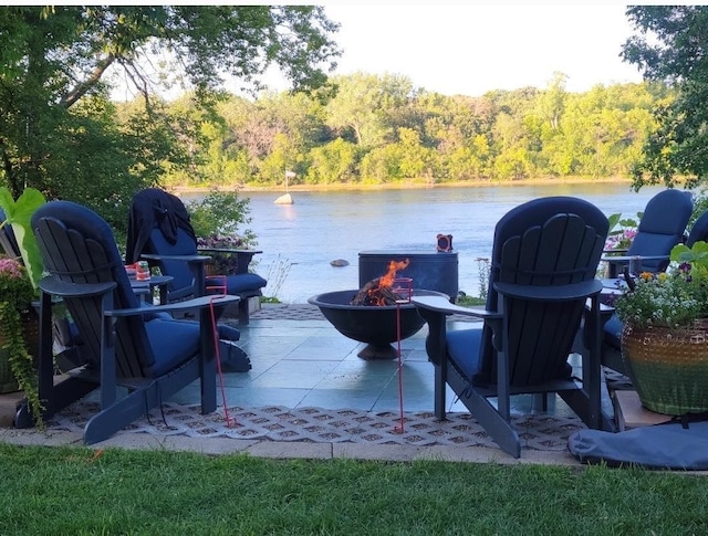 view of patio / terrace with a water view, a fire pit, and a view of trees