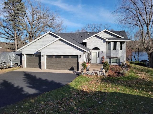 tri-level home with driveway, a garage, and a front lawn