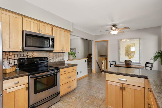 kitchen with dark countertops, stainless steel appliances, backsplash, and light brown cabinetry