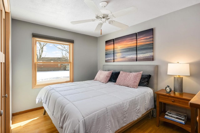 bedroom with a ceiling fan, baseboards, and wood finished floors