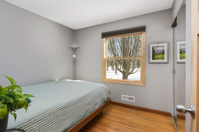 bedroom with visible vents, baseboards, and wood finished floors