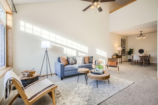 carpeted living room featuring ceiling fan with notable chandelier, a high ceiling, and baseboards