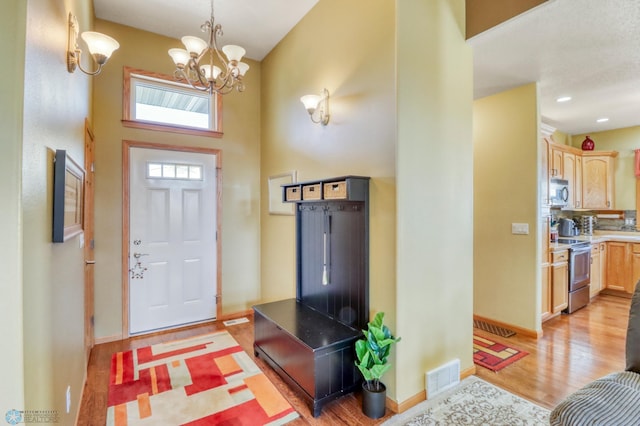 entrance foyer with a chandelier, visible vents, light wood-type flooring, and baseboards