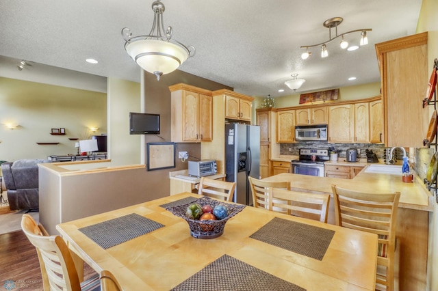 kitchen with light brown cabinets, decorative backsplash, appliances with stainless steel finishes, and a sink