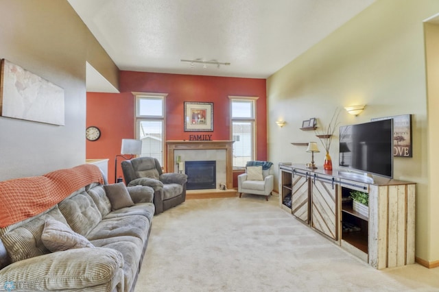 living area featuring a glass covered fireplace, track lighting, carpet, and a wealth of natural light