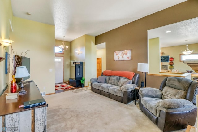 living room with visible vents, baseboards, an inviting chandelier, a textured ceiling, and carpet flooring