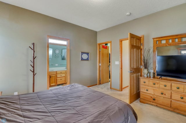 bedroom featuring a textured ceiling, baseboards, ensuite bathroom, and light carpet