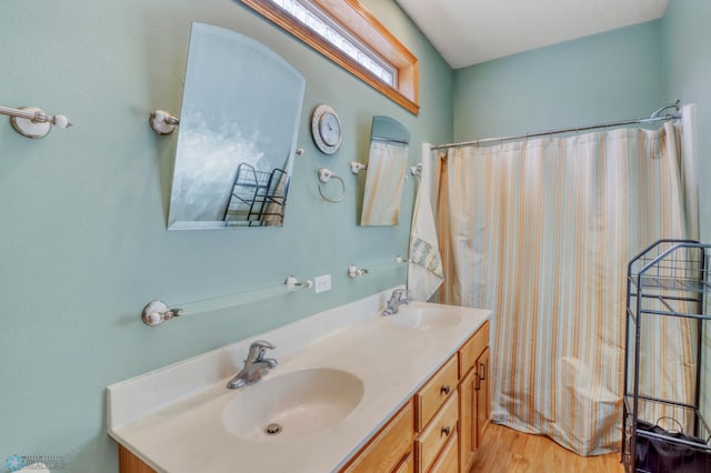 bathroom with a sink, curtained shower, wood finished floors, and double vanity