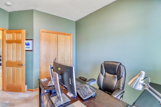 carpeted office with baseboards and a textured ceiling