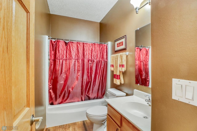 bathroom with vanity, wood finished floors, shower / bath combo with shower curtain, a textured ceiling, and toilet