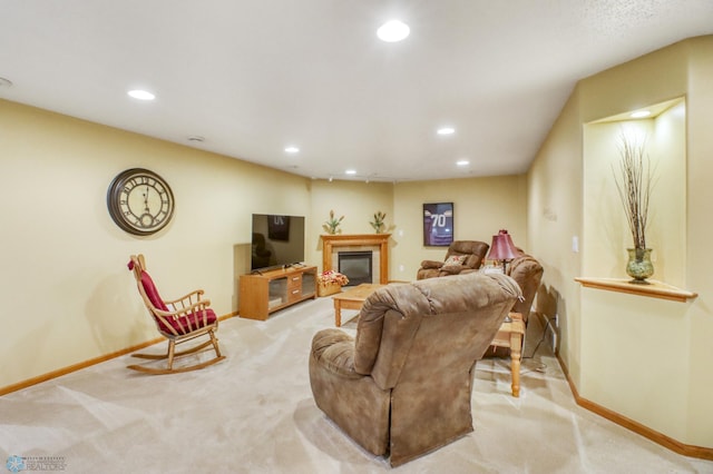 living area featuring a glass covered fireplace, recessed lighting, baseboards, and light carpet