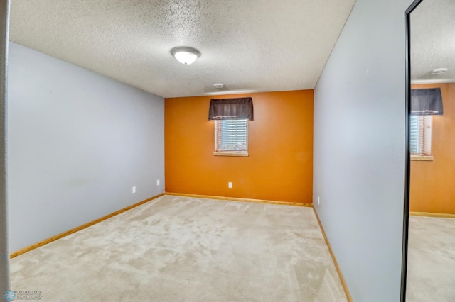 carpeted spare room with baseboards and a textured ceiling