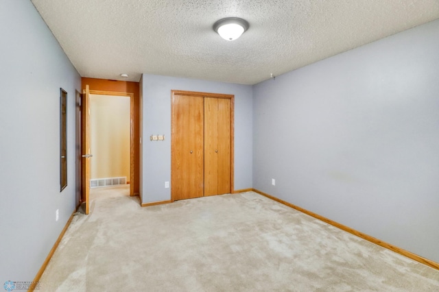 unfurnished bedroom with baseboards, visible vents, a closet, a textured ceiling, and carpet flooring