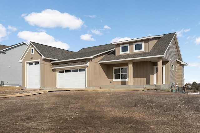 view of front of property featuring driveway, a garage, and roof with shingles