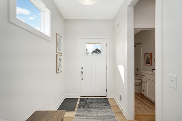 entryway with visible vents, plenty of natural light, baseboards, and light wood-style flooring