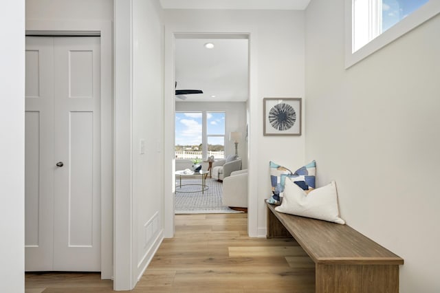 corridor with light wood finished floors, visible vents, and recessed lighting