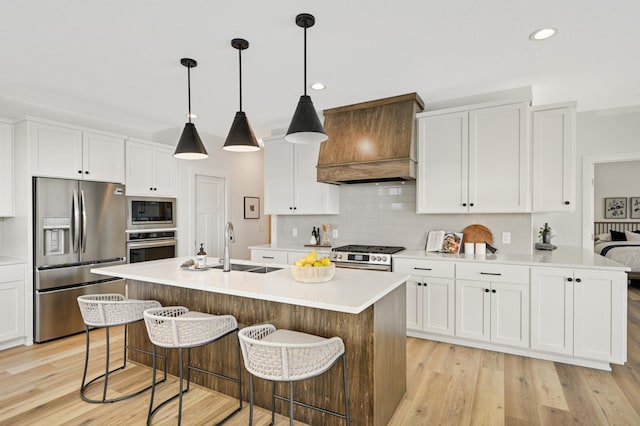 kitchen with premium range hood, a sink, stainless steel appliances, light wood-style floors, and backsplash