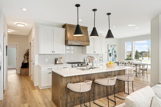 kitchen featuring premium range hood, backsplash, a breakfast bar, and a sink