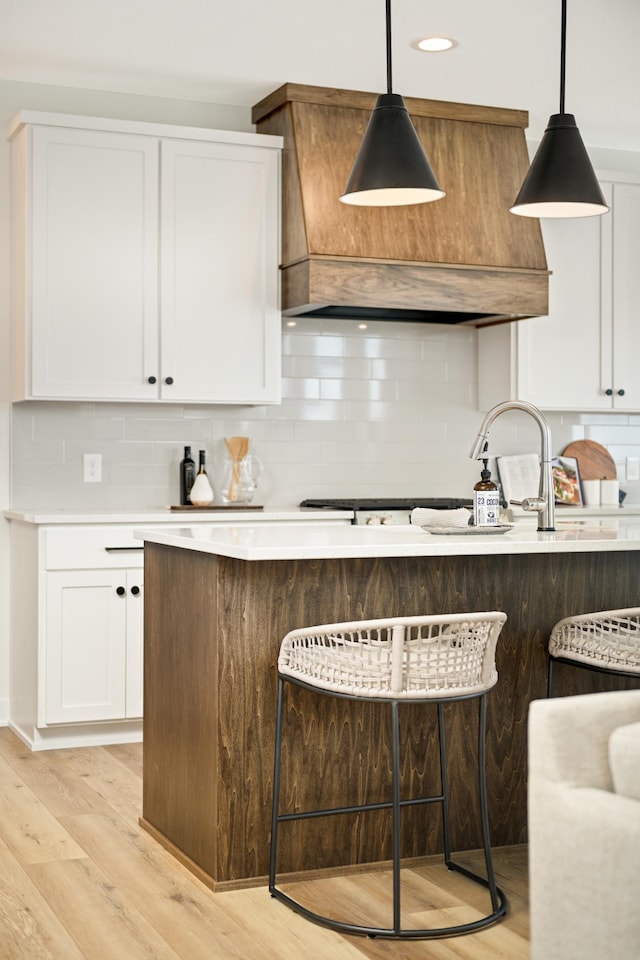 bar with custom range hood, tasteful backsplash, pendant lighting, and light wood finished floors