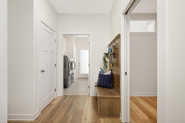 corridor with light wood-type flooring, baseboards, and separate washer and dryer