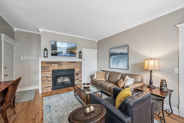 living area with baseboards, a stone fireplace, light wood-style flooring, and crown molding