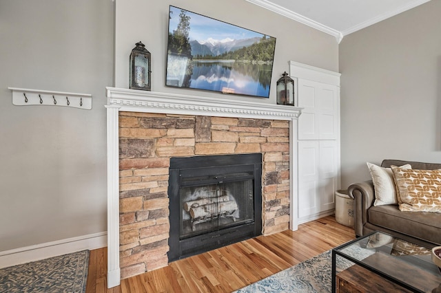 living room featuring a fireplace, crown molding, baseboards, and wood finished floors