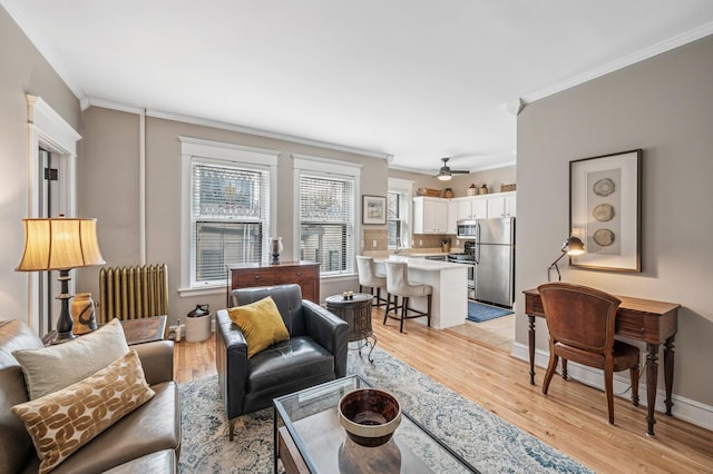 living room with baseboards, light wood-style flooring, radiator heating unit, and crown molding