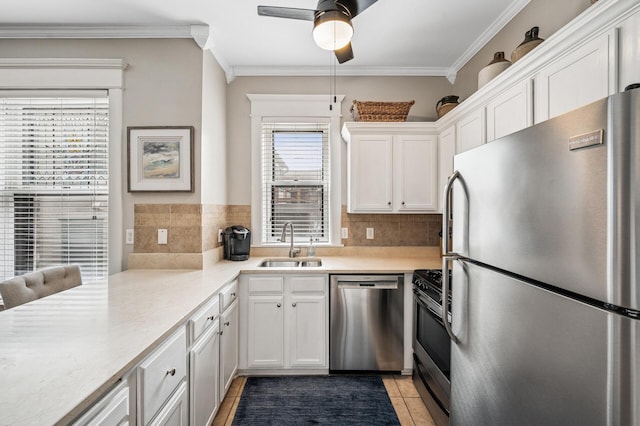 kitchen featuring a ceiling fan, a sink, stainless steel appliances, white cabinetry, and crown molding