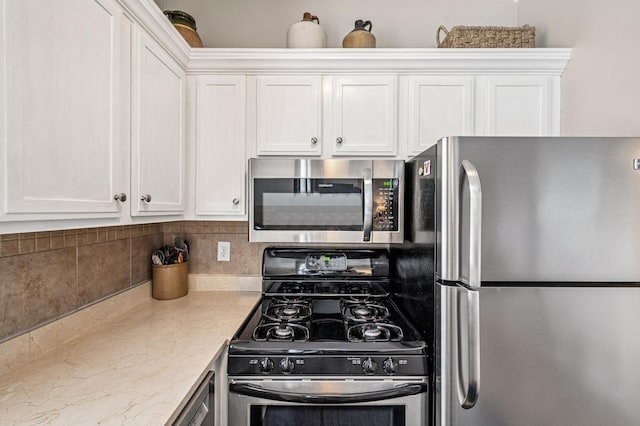 kitchen with white cabinets, stainless steel appliances, and light stone countertops