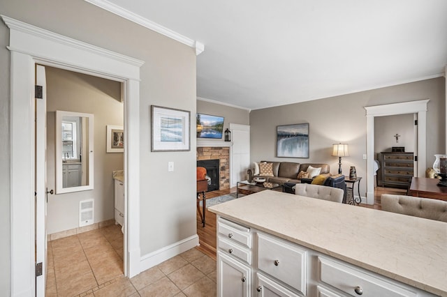 kitchen featuring crown molding, light stone countertops, open floor plan, light tile patterned flooring, and white cabinets