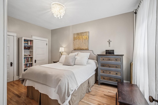 bedroom featuring an inviting chandelier and light wood finished floors