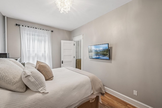 bedroom featuring baseboards, a notable chandelier, and wood finished floors